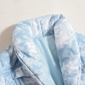 Détail de la veste matelassée à col montant avec motif tie-dye nuages bleu et blanc