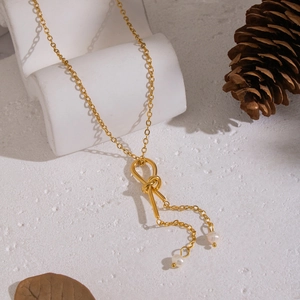 Golden knot sweater chain with tassel and fresh water pearls on geometric display stand