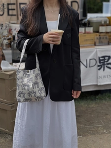 Close-up of cream canvas tote bag with black animal embroidery held by a model
