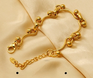 Détail du bracelet gourmette en acier doré sur tissu en soie luxueuse de haute qualité