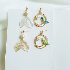 Detail view of asymmetric whale tail earrings with pearls and gradient enamel finish