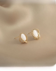 Detail of gold cat-eye stone earrings featuring intricate micro-beaded metal craftsmanship