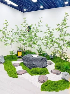 Zen garden scene featuring artificial silk moss, faux bamboo, and white pebbles decor