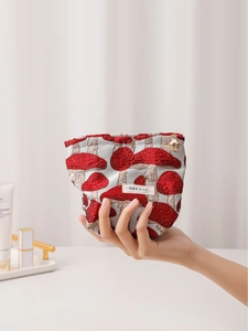 Vintage mushroom jacquard makeup bag with gold zipper held against a vanity backdrop