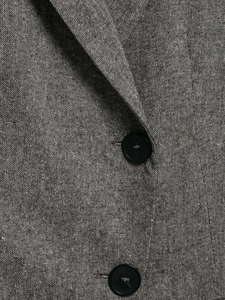 Close-up detail of grey textured blend fabric with black round buttons on a women suit