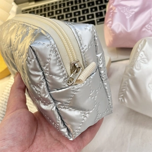 Close-up of a silver quilted makeup bag with dotted diamond pattern and zip closure