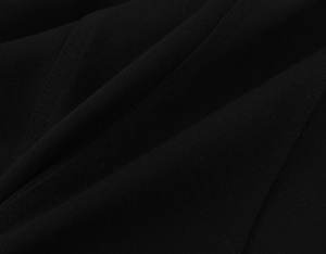 Gros plan macro du tissu crêpe noir montrant le tissage sergé et les plis du vêtement