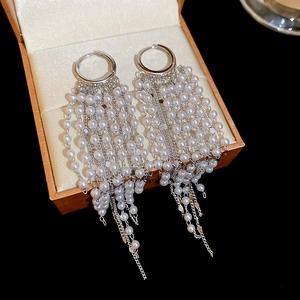 Macro detail of 18k gold plated long pearl tassel earrings in a premium jewelry box