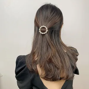 Detail view of a round pearl hair clip with small rhinestones on an elegant hairstyle