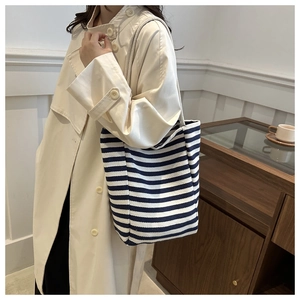 Lifestyle shot of blue and white striped canvas tote bag styled with a beige trench coat