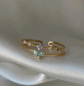 Vue macro d'une bague dorée papillon et fleur avec cristaux violets et verts étincelants