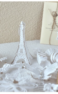 Macro shot of white and champagne glitter Eiffel Tower with butterfly Christmas ornaments