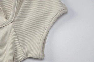 Macro shot showing the beige ribbed knit fabric texture and high-quality cuff stitching