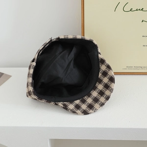 Detail of vintage brown plaid newsboy cap showing the black fabric lining and warm wool texture