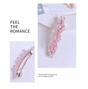 Detailed view of pink crystal bead hair clip with metal fastener on white background