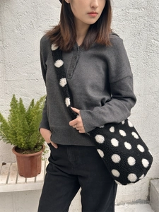 Gros plan du sac seau en peluche à pois avec large bandoulière porté par un mannequin