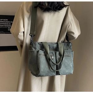 Detail of green corduroy crossbody bag with multiple zip pockets and adjustable strap