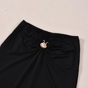 Detail of black knit skirt featuring a gold seashell metal buckle and pleated waist detail