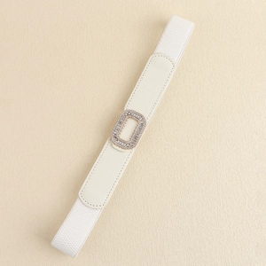 Detail of white elastic waist belt featuring a gold rectangular buckle with crystal accents