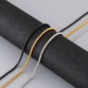 Detailed view of silver, gold, and black stainless steel box chains on a display stand
