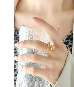 Détail d'une bague ouverte en acier inoxydable doré avec perles portée à la main