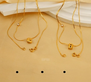 Close-up of golden stainless steel E and B letter pendants with inlaid cubic zirconia
