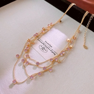 Detail of layered gold necklace featuring lavender crystal charms and adjustable link chain