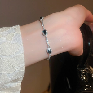 Detail view of a silver bracelet with three oval blue zircons and small diamonds on wrist