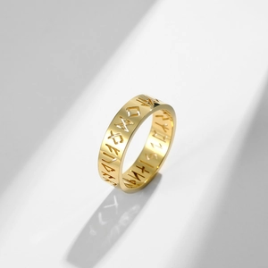 Detailed view of golden hollow Viking rune ring with dramatic side lighting and shadows