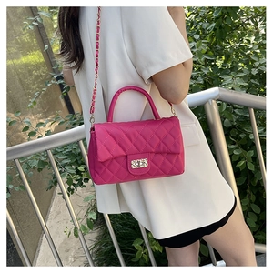 Detailed macro view of the rose red quilted texture and elegant gold chain strap on the handbag