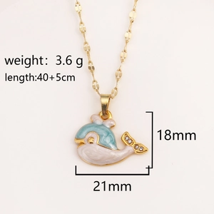 Collana con ciondolo a forma di balena dorata in smalto blu e strass su sfondo beige