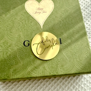 Detail of green embossed gift box featuring golden Feliz Cumple acrylic cake topper
