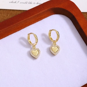 Macro detail of gold-plated heart earrings with sparkling white cubic zirconia stones