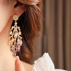 Detailed close-up of a vintage gold earring with purple and white gradient stones on a model