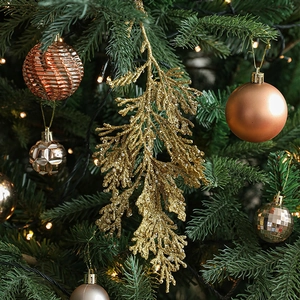 Golden glitter artificial cypress leaves and metallic ornaments on a festive Christmas tree