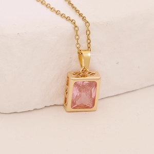 Macro shot of pink zirconia pendant on golden necklace with intricate floral pattern