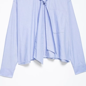 Women's light blue long sleeve shirt featuring a bow tie collar and front pocket detail
