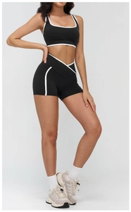 Close-up of black yoga set featuring U-neck contrast top and crisscross waist shorts