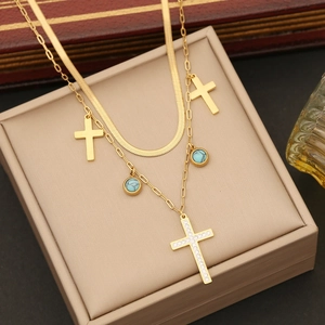 Double layered gold necklace with turquoise stones and shimmering cross pendants on a jewelry box