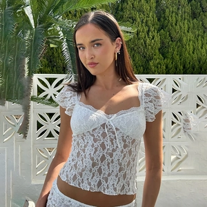 Nahaufnahme der weißen floralen Spitzenstruktur und Stickerei am eng anliegenden Crop Top