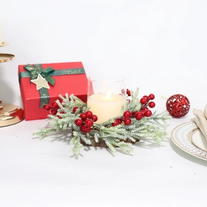 Frosted pine candle ring with red berries and a lit candle on a rustic wooden base