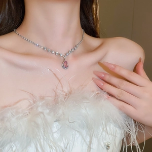 Elegant model wearing a silver necklace with pink teardrop pendant and crystal accents