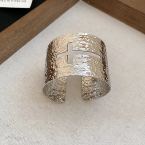 Détail d'un bracelet manchette argenté martelé avec motif croix évidé sur lin