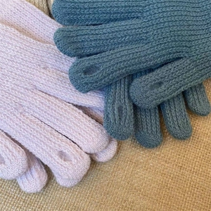 Dettaglio guanti in maglia rosa e blu scuro con funzione touch su sfondo di lino