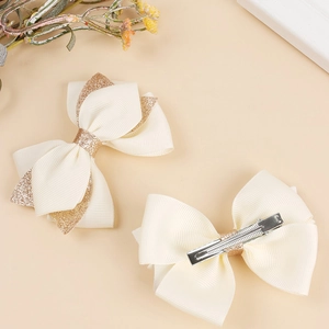 Beige ribbed ribbon hair clips with gold glitter accents and metal alligator grip