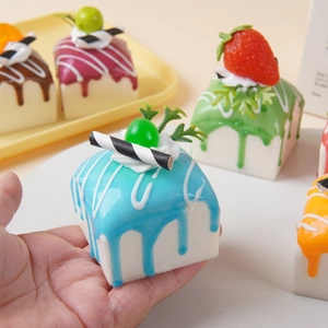 Handheld view of realistic square PU faux dessert cake model with vibrant colorful fruit toppings