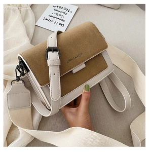 Detail of two-tone crossbody bag with canvas and leather straps on elegant background