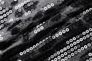 Vue macro de tissu à paillettes argentées sur maille noire montrant la texture brillante
