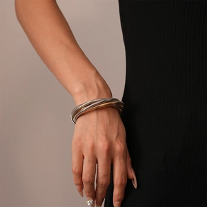 Nahaufnahme eines dreifarbigen Schlangenknochen-Armbands aus Metall am Damenhandgelenk