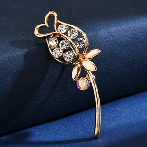 Detailed view of a golden rose brooch with rhinestones on a blue velvet backdrop